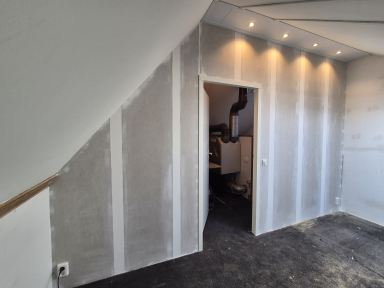 Nieuwe tussenwand behangklaar met toegangsdeur.